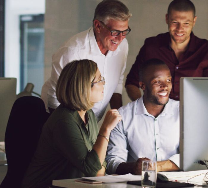 Cropped shot of a group of businesspeople working together on a computer in their office